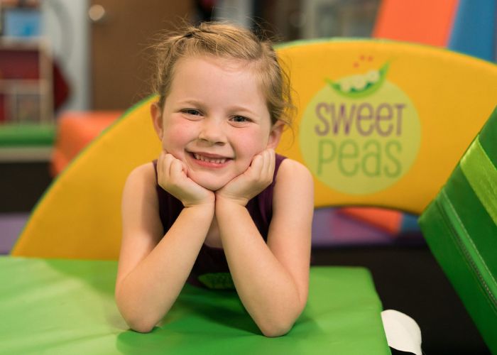 Sweet peas young gymnast smiling on top of equipment in preschool section
