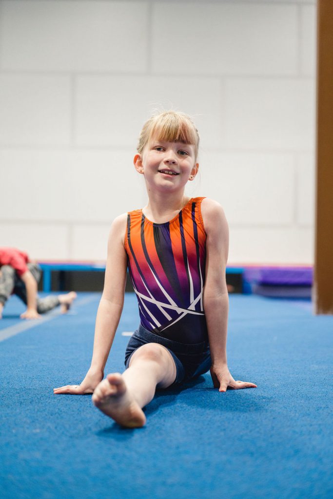 young gymnast stretching and doing the splits in her first class