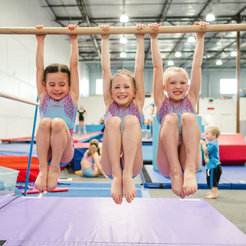 rec girls smiling hanging on a gymnastics bar