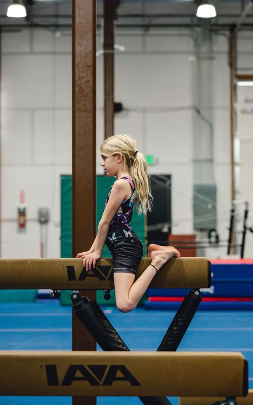 Overcoming Fear young gymnast sitting on a beam focused