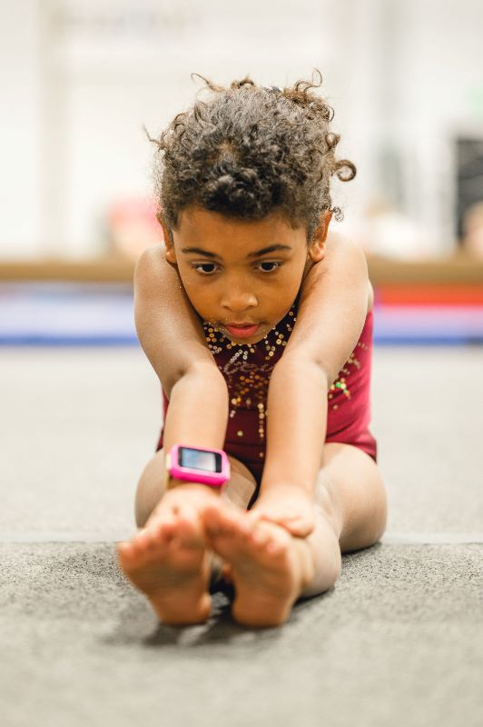 Common Gymnastics Injuries girl stretching before practice to warm up