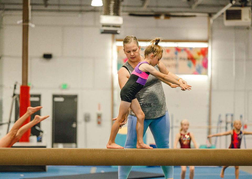 gymnastics terms coach spotting kid on the beam