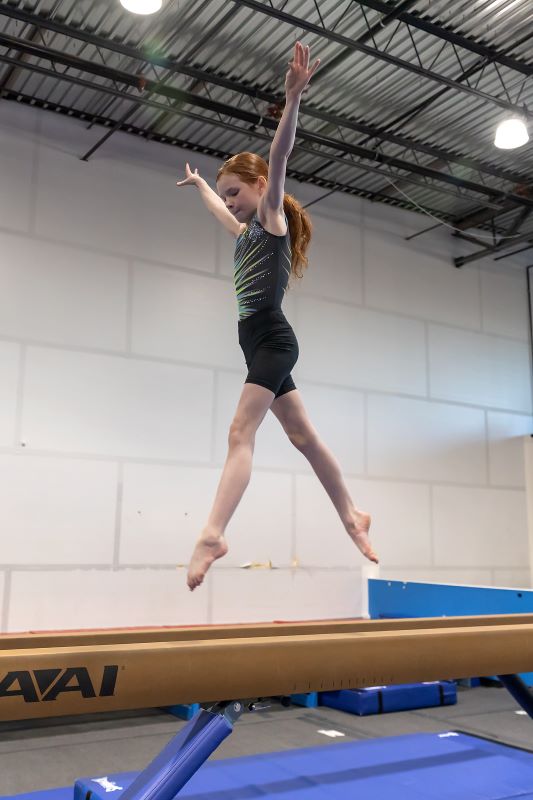 artistry gymnast jumping on a beam