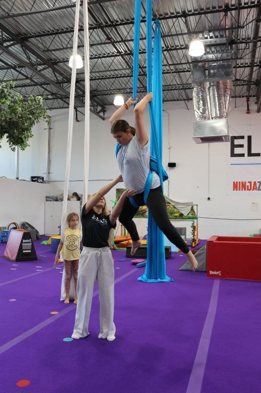 aerial silks practicing at height with a coach spotting