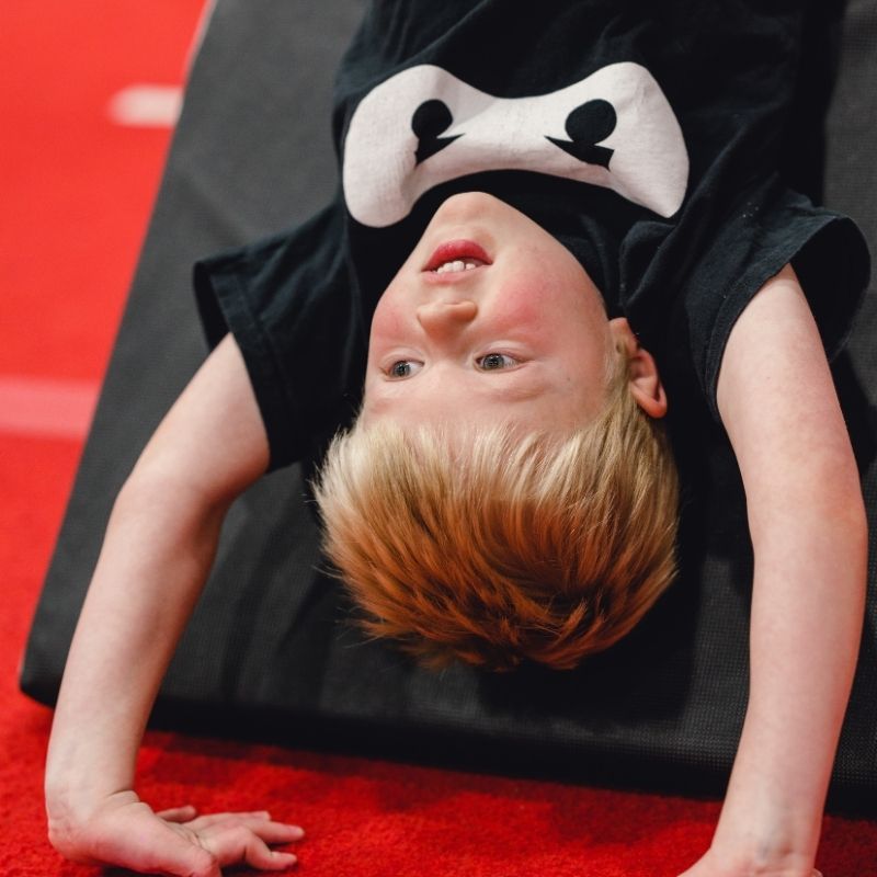 Consistency young ninja practicing his bridge on a mat