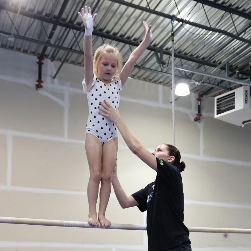 Choose the Right Class youn gymnast being spotted by a coach