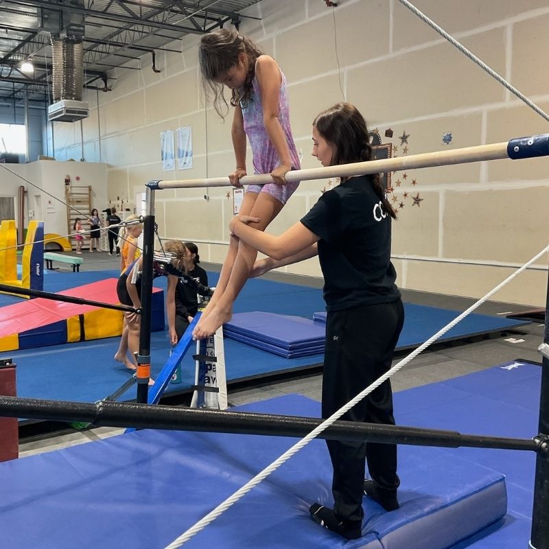 kids activity coach spotting kid and helping them learn a new skill