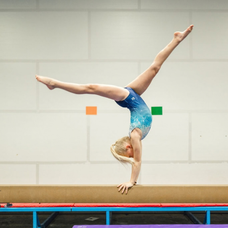 Growth spurt kid doing a handstand on a beam